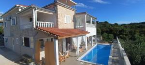 a house with a swimming pool in front of it at Apartments Solta in Nečujam