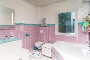 a pink bathroom with a tub and a toilet at Villa du Leman in Thonon-les-Bains