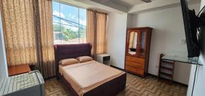 ein Schlafzimmer mit einem Bett, einer Kommode und einem Fenster in der Unterkunft Makasai Habitaciones in Puerto Maldonado