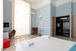 a bedroom with a white bed and a tv and a couch at Napolit'amo Hotel Principe in Naples