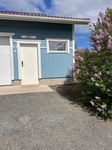 uma casa azul com uma porta branca e um arbusto em Puuppola Kotikoivu 