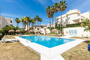 una piscina en el patio trasero de una casa con palmeras en La Quinta Hills - Modern Andalusian-style home with rooftop Terrace en Marbella