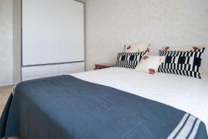 1 dormitorio con 1 cama grande con almohadas blancas y negras en Appartement vue imprenable sur la baie des Sables - 4 personnes, en Les Sables-dʼOlonne