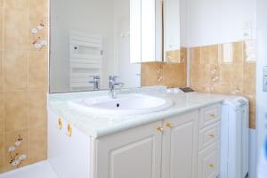 Un baño con un lavabo blanco y un espejo. en Appartement vue imprenable sur la baie des Sables - 4 personnes, en Les Sables-dʼOlonne