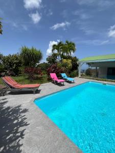 una piscina con due sedie a sdraio e una casa di Le jardin des B-joux a Le Morne-Vert
