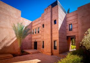 ein Gebäude mit einer Palme davor in der Unterkunft Riad Tamazgha in Marrakesch