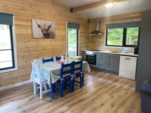 a kitchen with a table with blue chairs in a room at Rosies Cabin Maum in Galway
