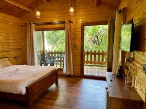 a bedroom with a bed in a wooden cabin with a balcony at Coorg Jungle Mist in Madikeri