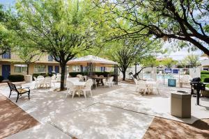 a patio with white chairs and tables and trees at Motel 6-Holbrook, AZ in Holbrook