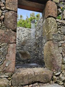 an opening in a stone wall with a window at Aldeia da Cuada in Faja Grande