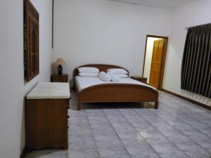 a bedroom with a bed and a tiled floor at villa kumala in Tjikakaka