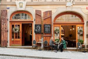two people sitting at a table outside of a restaurant at Hotel Nerudova 211 in Prague