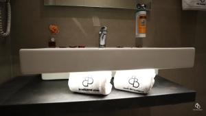 un lavandino in bagno con due asciugamani sotto di Hotel Ben Batouta - Tanger a Tangeri
