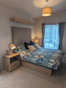 a bedroom with a bed and a lamp and a window at LUXURY STUNNING SENSATION LODGE ON 5 STAR SHOREFIELD COUNTRY PARK New Forest ENTERTAINMENT AND LEISURE PASSES INCLUDED in Milford on Sea