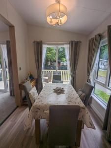 a dining room with a table and chairs and a window at LUXURY STUNNING SENSATION LODGE ON 5 STAR SHOREFIELD COUNTRY PARK New Forest ENTERTAINMENT AND LEISURE PASSES INCLUDED in Milford on Sea