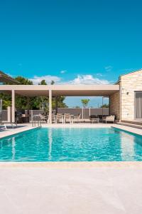a swimming pool with tables and chairs on a building at Terra Petra Luxury Villas by Travel Pro Services- Vourvourou Halkidiki in Vourvourou