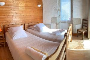 2 łóżka w pokoju z drewnianą ścianą w obiekcie Le P'tit Gîte w mieście Pellegrue