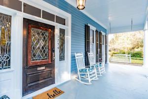 a porch with rocking chairs and a wooden door at Heavenly on Hunter-Historic Grandeur-The Cannon in Mobile