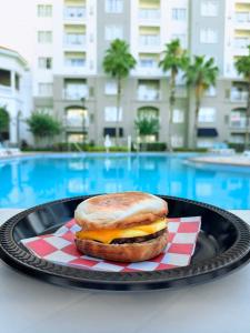 a sandwich on a plate on a table near a pool at The Point Hotel & Suites Universal in Orlando