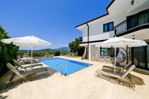 a villa with a swimming pool and two umbrellas at Mediterranean Breeze Villa - Family-Friendly Luxury Villa - Fethiye by Sunworld Villas in Fethiye