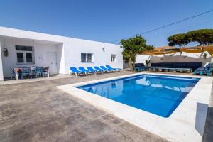 una piscina en un patio con sillas azules y una casa en Parisito Sancti Petri, en Chiclana de la Frontera