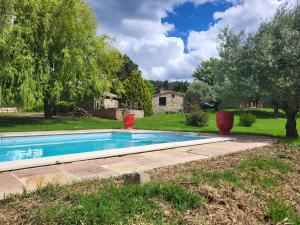 a swimming pool in a yard with two vases at Mas de Bouilhac 1 Gite, 1 Chambre Insolite, 1 Chambre Romantique in Pranles