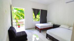 ein Zimmer mit zwei Betten, einem Stuhl und einem Fenster in der Unterkunft Hotel Vias Maya Bacalar in Bacalar