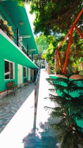 un bâtiment vert avec un palmier devant lui dans l'établissement Hotel Vias Maya Bacalar, à Bacalar