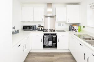 una cocina blanca con armarios blancos y un aparato negro en Modern Luxury 5 Bedroom House en Chatham