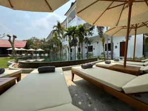 un patio con bancos y sombrillas y una piscina en The Urban, en Siem Reap
