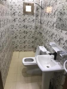 een badkamer met een wit toilet en een wastafel bij Hôtel Ami Bamba in Mbour