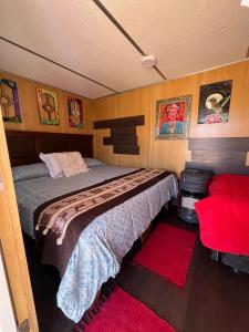 1 dormitorio con 2 camas y sofá rojo en Retiro Bajoestrellas, en San Pedro de Atacama