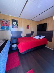 1 dormitorio con 1 cama grande de color rojo y TV de pantalla plana en Retiro Bajoestrellas, en San Pedro de Atacama