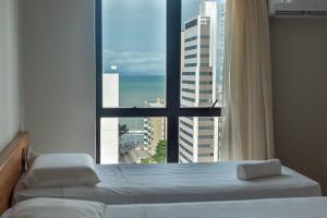 a bedroom with a view of the ocean from a window at Rede Andrade Onda Mar in Recife