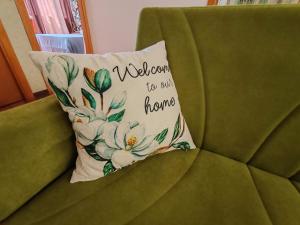 un cuscino di benvenuto su un divano verde di OSTIA HOME a Lido di Ostia