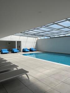 - une piscine avec des chaises bleues dans un bâtiment dans l'établissement Sesimbra Blue Paradise, à Sesimbra