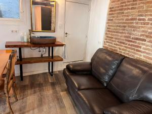 um sofá de couro numa sala de estar com uma parede de tijolos em Cataluña Room em Barcelona
