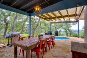a wooden table and chairs on a patio with a pool at Modern Fischer House with Deck, Fire Pit and Hot Tub! in Fischer