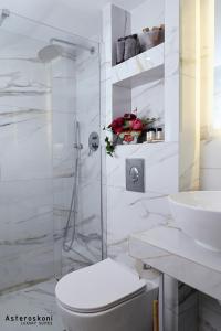 a white bathroom with a toilet and a sink at Asteroskoni Luxury Suites in Nafplio +35 photos