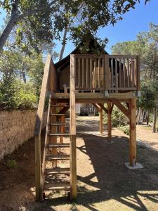 a wooden tree house with a staircase at Camping Santa Elena in Lloret de Mar