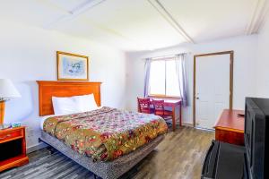 Schlafzimmer mit einem Bett, einem Schreibtisch und einem TV in der Unterkunft Country Hearth Inn & Suites By OYO Sturgis in Sturgis