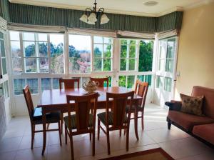 a dining room with a table and chairs and windows at Casa Sanmartín in Maside