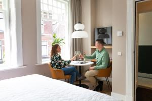 a man and woman sitting at a table in a hotel room at Boutique Pastorale in Linschoten