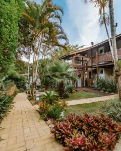 uma casa com palmeiras e uma passarela em Hospedaria das Brisas na Praia do Rosa