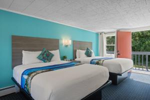 a hotel room with two beds and a balcony at Olde Tavern Motel and Inn - Cape Cod in Orleans