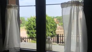 Una ventana con cortinas blancas y vista a un patio. en Casas Navarredonda, en Navarredonda