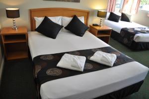 a hotel room with two beds and two nightstands at Meadowbrook Hotel Brisbane in Loganlea