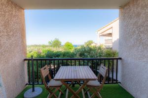 Una mesa de madera y dos sillas en un balcón. en Sanary Bandol plein SUD, en Sanary-sur-Mer