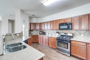 a kitchen with wooden cabinets and a stove top oven at Houston Retreat with Pool Access and Fenced-In Yard! in Houston