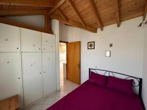 Un dormitorio con una cama morada y armarios blancos. en Eva's Apartments, en Karlovasi